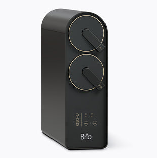 A sleek, black Brio appliance with two circular dials on the front, labeled CO2 and H2O, and touch controls below, designed for dispensing carbonated water.